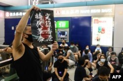 2019年8月21日,香港示威者在元朗西铁站高举海报，抗议他们指责的“警黑勾结”导致元朗暴徒袭击示威者事件。