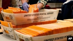 FILE - Election officials sort absentee and early voting ballots for counting inside Boston City Hall in Boston, Nov. 2, 2020.