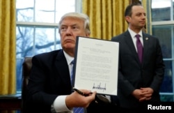 U.S. President Donald Trump holds up the executive order on the reinstatement of the Mexico City Policy after signing in the Oval Office of the White House in Washington, Jan. 23, 2017.