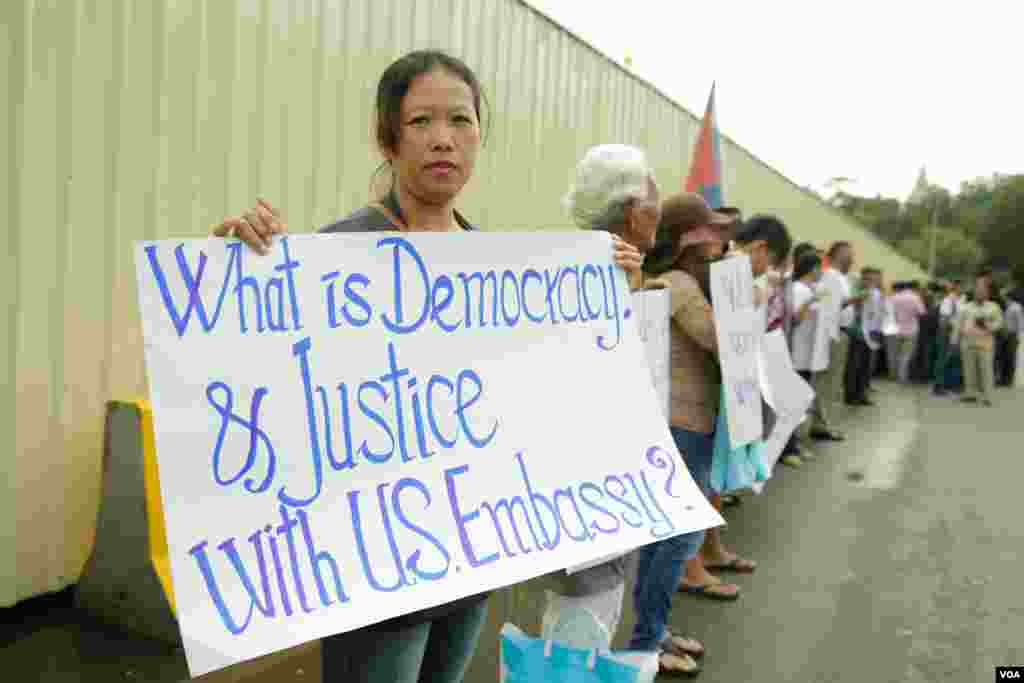 សន្តិសុខ​ដែល​ត្រូវ​បាន​ស្ថានទូត​សហរដ្ឋ​អាមេរិក​បញ្ឈប់​កាល​ពី​ប៉ុន្មាន​ខែ​មុន​​​និង​គ្រួសារ​របស់ពួកគេ​បាន​មក​ធ្វើ​បាតុកម្ម​តវ៉ា​រក​យុត្តិធម៌​ដោយ​អហិង្សា​នៅ​ខាង​មុខ​ស្ថានទូត​អាមេរិករាជធានី​ភ្នំពេញ​ ​កាល​ពីព្រឹក​ថ្ងៃទី​១៩ មិថុនា ឆ្នាំ ២០១៨។(ទុំ ម្លិះ/VOA)