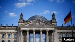 FILE - A German flag flutters in front of the Reichstag building in Berlin, Germany, Sept. 6, 2020. The inscription on the building reads "[Dedicated] to the German people."