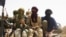 Fighters from Islamist group Ansar Dine stand guard during the handover of a Swiss female hostage for transport by helicopter to neighboring Burkina Faso, at a designated rendezvous point in the desert outside Timbuktu, Mali Tuesday, April 24, 2012. Two m