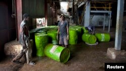 FILE - Workers are seen pushing barrels of vegetable oil.