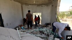 مردم در حال تفتیش خانه‌ای در ابلین، جنوب استان ادلب، که در اثر حملات توپخانه‌ای شنبه ١٢ تیر نیروهای دولتی سوریه ویران شد. (منبع: آسوشیتدپرس)