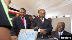 Kenyan President Mwai Kibaki (R) registers as a voter before launching the nationwide, one-month biometric voter registration (BVR) exercise in the capital Nairobi, November 19, 2012.