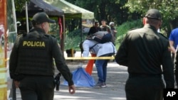 A forensic investigator inspects the remains of a man killed when a motorcycle loaded with explosives detonated at a police checkpoint in Las Peñas community of Jamundi, Colombia, Dec. 7, 2024.