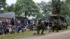Kenyan police officers hold their position as residents watch during an operation against a gunman at the Kapenguria police station in Kapenguria, western Kenya, July 14, 2016. 