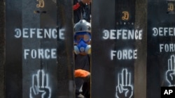 在仰光，抗议者站在防御安全部队的自制屏障的后面。(2021年3月11日)