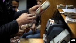 Warga Mesir menghitung uang di sebuah kantor penukaran valas di pusat kota Kairo (Foto: dok). Nilai mata uang Mesir kehilangan lebih dari 10 persen terhadap dolar tahun ini.
