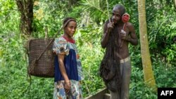 FILE - Members of the Bagyeli Pygmy community display their hunting equipment, May 26, 2017 in the Kribi region, Cameroon.