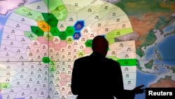 Staf perusahaan komunikasi satelit Inggris Inmarsat meneliti data satelit pesawat Malaysia Airlines yang hilang di kantor pusat mereka di London (25/3). (Reuters/Andrew Winning)