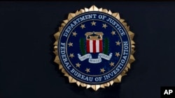 FILE - In this June 14, 2018, file photo, the FBI seal is seen before a news conference at FBI headquarters in Washington. The FBI is grappling with a seemingly endless cycle of money laundering schemes that law enforcement officials say they’re…