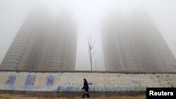 一名戴口罩的妇女走过中国河北邯郸的大楼旁。（2019年1月12日）