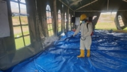 Petugas kesehatan menyemprotkan cairan disinfektan di tenda jelang pelaksanaan kegiatan psikososial di shelter Terintegrasi di Stadion Manakarra, Mamuju, Sulawesi Barat, Minggu, 31 Januari 2021. (Foto: Yoanes Litha/VOA)
