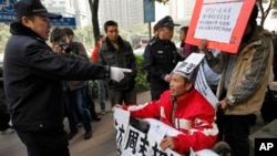 在《南方周末》广州总部外，警察指着一名声援《南方周末》的坐轮椅的抗议男子，随后把他带走。（2013年1月10日）