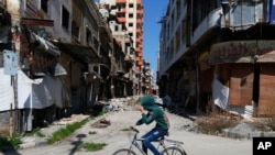 시리아 소년이 홈스에서 자전거를 타고 가고 있다.