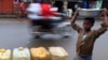 FILE - A young vendor walks past jerrycans of water for sale in central Monrovia, Liberia. Improvements in road maintenance are a major element of the MCC.