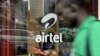 A man with his phone in hand walks past a window branded in an 'Airtel' logo on May 20, 2011 in the Kenyan capital, Nairobi. 
