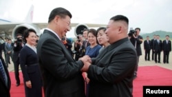 资料照：朝鲜领导人金正恩在平壤国际机场欢迎到访的中国国家主席习近平。（2019年6月21日）