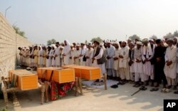 FILE - Afghan men offer funeral prayers near the bodies of civilians killed in a NATO airstrike, on the outskirts of Jalalabad, east of Kabul, Afghanistan, Oct. 5, 2013.