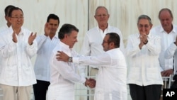 Presiden Kolombia Juan Manuel Santos (depan kiri) berjabat tangan dengan pemimpin FARC Rodrigo Londono usai penandatangan perjanjian damai di Cartagena, Kolombia 26 September lalu (foto: dok).
