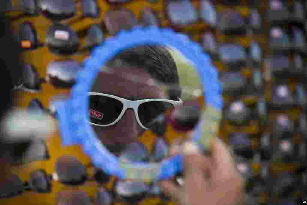 Seorang pria Pakistan melihat di kaca sebelum membeli kacamata hitam di pinggir jalan di Islamabad.