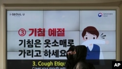 People wearing face masks pass by an electric screen about precautions against the illness COVID-19 in Seoul, South Korea, Tuesday, Feb. 18, 2020. A viral outbreak that began in China has infected more than 73,000 people globally. The World Health…