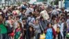 FILE-Cambodian migrant workers carry their belongings as they walk to cross the border at Aranyaprathet in Sa Kaew June 15, 2014. REUTERS/Athit Perawongmetha