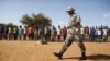 A Malian solider walks in front of people during a training camp of the FLN movement (North Liberation Forces) in Sevare September 24, 2012. The FLN is a part of a militia which trains youths from all over the country and operates in government-controlle