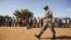 A Malian solider walks in front of people during a training camp of the FLN movement (North Liberation Forces) in Sevare September 24, 2012. The FLN is a part of a militia which trains youths from all over the country and operates in government-controlle