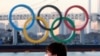 A man stands in front of a countdown clock for Tokyo Olympic and Paralympic Games in Tokyo, Feb. 3, 2021.