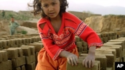 FILE - An Afghan girl makes a pile of unbaked bricks near the road passing through the Shamali Plains, about 10 kilometers ( 6 miles), west of Bagram, Afghanistan.