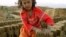 FILE - An Afghan girl makes a pile of unbaked bricks near the road passing through the Shamali Plains, about 10 kilometers ( 6 miles), west of Bagram, Afghanistan.