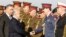 FILE - Iraqi Prime Minister Haider al-Abadi, second from left, shakes hands with military officials with Iraq Defense Minister Khaled al-Obeidi, left, during the Iraqi Army Day anniversary celebration, in Baghdad, Jan. 6, 2015. 
