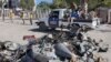 A police vehicle drives past wreckage after a suicide car bomb attack on a government building in Mogadishu, Somalia, March 23, 2019. Al-Shabab gunmen stormed the government building after a suicide car bombing.