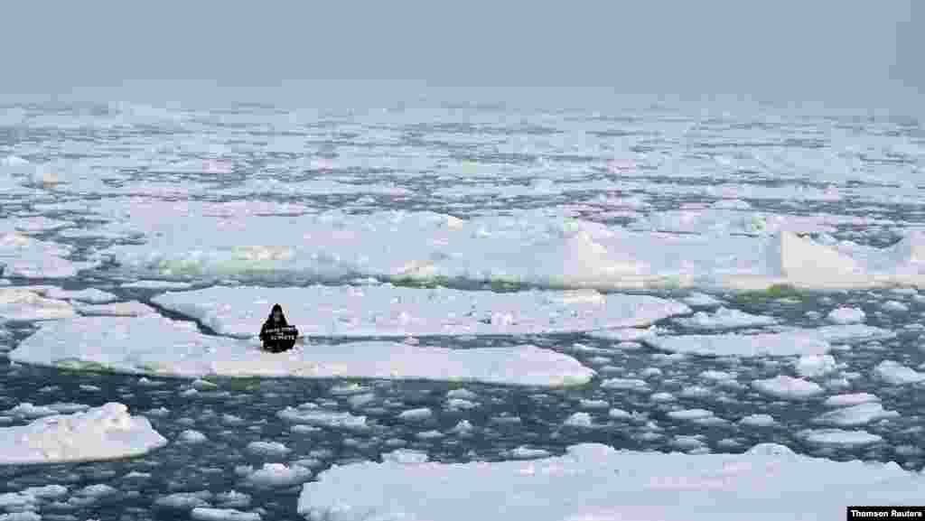 환경보호 운동가가 &#39;기후를 위한 청소년 파업(Youth Strike for Climate)&#39;이란 현수막을 들고 북극해의 부빙 위에 앉아 있다. 