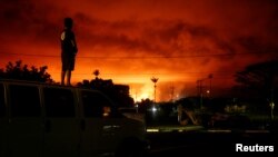 Darryl Sumiki, 52, of Hilo, watches as lava lights up the sky above Pahoa during ongoing eruptions of the Kilauea Volcano in Hawaii, June 2, 2018. 