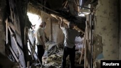 우크라이나 동부 도네츠크의 주거지역이 18일 밤 폭격을 받은 가운데 주민들이 파괴된 건물 안에서 잔해물을 정리하고 있다.