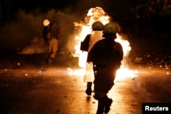 A petrol bomb explodes among riot policemen during clashes following a rally marking the 44th anniversary of a 1973 student uprising against the military dictatorship that was ruling Greece, in Athens, Greece, Nov. 17, 2017.