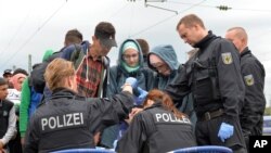 German policemen register refugees at the rail station in Freilassing, southern Germany, Sept. 14, 2015, before they take them away in busses.