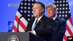 Le président américain Donald Trump, à droite, écoute le secrétaire d'Etat américain Mike Pompeo lors d'une conférence de presse après un sommet des chefs d'Etat et de gouvernement au siège de l'OTAN à Bruxelles, en Belgique, le 12 juillet 2018.