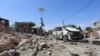 Somali policemen look at the wreckage of a destroyed car at the scene of a suicide attack at a checkpoint outside the main base of an African Union peacekeeping force in the Somali capital Mogadishu, Jan. 2, 2017. 