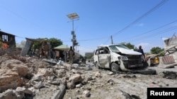 Somali policemen look at the wreckage of a destroyed car at the scene of a suicide attack at a checkpoint outside the main base of an African Union peacekeeping force in the Somali capital Mogadishu, Jan. 2, 2017. 
