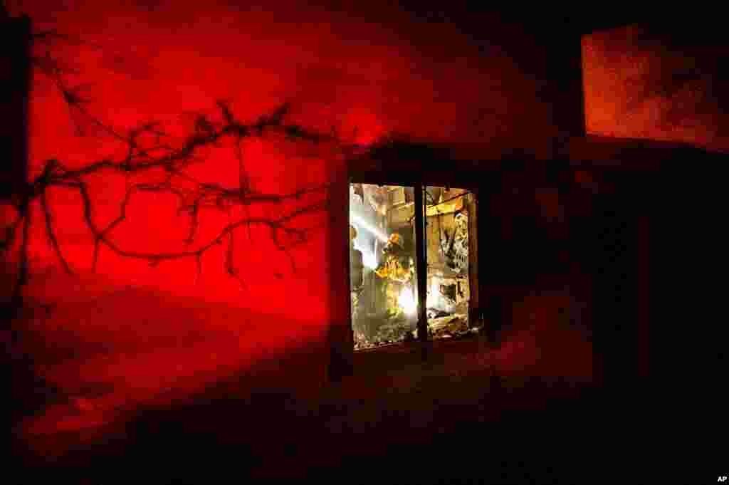 미국 캘리포니아 모노 카운티에 화재가 발생한 가운데 집을 에워싼 불길을 소방관이 진압하고 있다. 