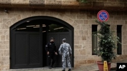 A private security guard speaks with a policeman at the residence of former Nissan chairman Carlos Ghosn, in Beirut, Lebanon, Dec. 31, 2019.