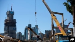 工人们在北京中心商业区的一处新开发项目工地搬走已被拆毁的旧址的一座钢柱。（2015年6月30日）