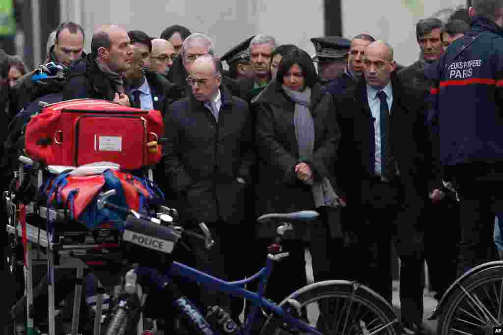 وزير کشور فرانسه، بارنارد کازنو (وسط چپ) و شهردار پاريس، آن ايدالگو (وسط راست) &nbsp;به ساختمان محل دفاتر هفته&zwnj;نامه طنز فرانسوی شارلی ابدو در پاریس آمده اند --&nbsp;۱۷ دیماه ۱۳۹۳ (۷ ژانويه ۲۰۱۵)