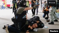 香港警察在逮捕一名参加反对港版国安法游行示威者的同时举起手中的胡椒喷剂手枪。（2020年7月1日）