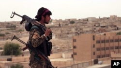 这张叙利亚民主军2017年4月30日提供的照片显示一名携带武器叙利亚民主军战士注视着叙利亚北部城镇塔布卡。