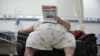 FILE - An obese person is seen reading a newspaper.